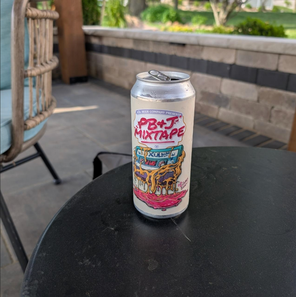 Xül Beer Company – PB&J Mixtape: Grape

ABV: 5,0 % | Stil: Fruited Sour Ale | Untappd: 4,38

PB&J Mixtape: Grape er en af de øl, som har gjort Xül Beer Company berømt langt uden for Tennessee. Inspirationen er enkel: den klassiske peanutbutter- og druesandwich fra barndommen. Resultatet er en overraskende autentisk sour, hvor Concord-druer og ristede peanuts skaber en oplevelse, der næsten føles som flydende PB&J.